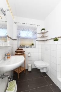 ein weißes Badezimmer mit Waschbecken und Toilette in der Unterkunft Ferienwohnungen im Haus Friedeburg in Carolinensiel
