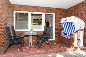 eine Terrasse mit einem Tisch und Stühlen an einer Ziegelwand in der Unterkunft Ferienwohnungen im Haus Friedeburg in Carolinensiel
