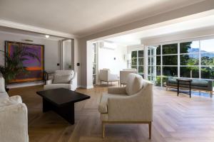 a living room with chairs and a table and windows at Bay Haven Collection in Cape Town