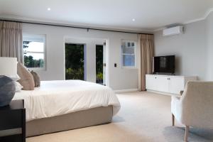 a bedroom with a bed and a tv and a chair at Bay Haven Collection in Cape Town