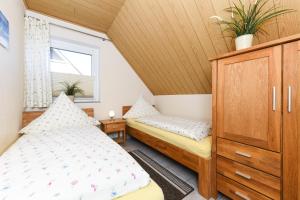 1 Schlafzimmer mit 2 Betten, einem Schrank und einem Fenster in der Unterkunft Ferienwohnungen im Haus Friedeburg in Carolinensiel