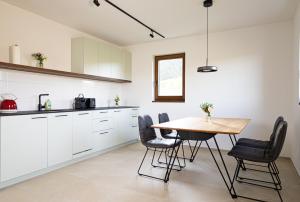 a kitchen with white cabinets and a wooden table at Kellerstöckel Steinbach in Gamlitz
