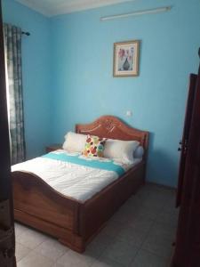 - un lit avec une tête de lit en bois dans une pièce bleue dans l'établissement Appartement Confortable dans la résidence Nyabaye, à Bertoua