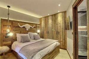 a bedroom with a bed with a wooden wall at ARC 1950, Appartement style Chalet Haut de Gamme 2 chambres, 6 personnes in Arc 1950 +43 photos