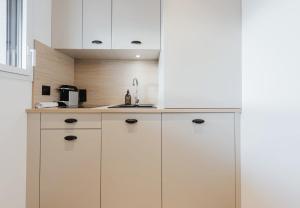 a kitchen with white cabinets and a sink at Appart Hotel Neostelia in Annecy
