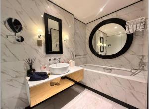 un bagno con un lavandino, una vasca e uno specchio di Atria Business Bay a Dubai