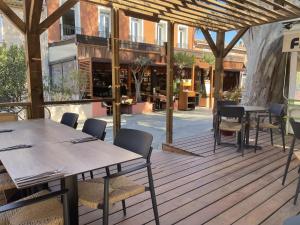 a patio with tables and chairs on a wooden deck at L'Oustaou De Porquerolles in Porquerolles