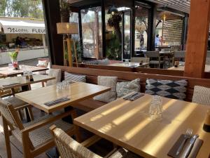 a restaurant with wooden tables and chairs in front of a store at L'Oustaou De Porquerolles in Porquerolles