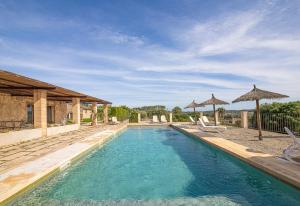 a swimming pool with chairs and umbrellas next to a house at Apartamento Son Calo B by Rentallorca in Petra