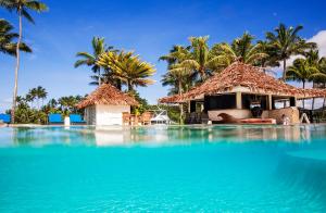 a resort with a swimming pool and palm trees at The Pearl South Pacific Resort, Spa & Golf Course in Pacific Harbour