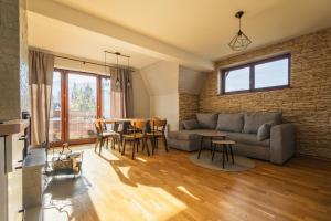 a living room with a couch and a table at Apartament Widokowy HELLO TATRY - Basen & Sauna Koscielisko in Kościelisko