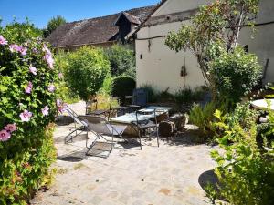 patio con sedie, tavolo e alcuni fiori di Maison curieuse - hammam et spa a Épisy
