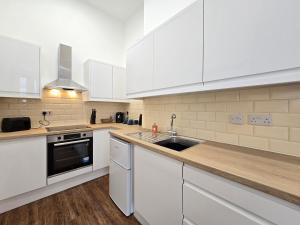 a kitchen with white cabinets and a sink at Two bedroom flat in Cardiff Bay with roof terrace in Cardiff +9 photos