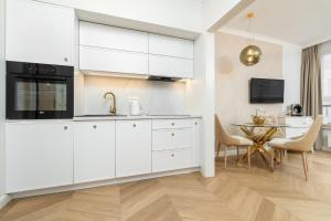 Una cocina con gabinetes blancos y una mesa. en MARGI Gold STUDIO, VERY LUX, OLD TOWN, AIRCON, en Szczecin