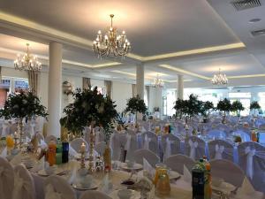 a large banquet hall with white tables and chairs at URychertow in Kiełpino