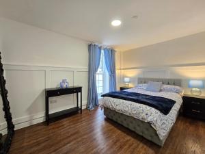 a bedroom with a bed and a window with blue curtains at Two bedroom flat in Cardiff Bay with roof terrace in Cardiff