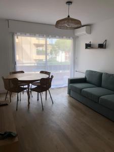 ein Wohnzimmer mit einer Couch und einem Tisch und Stühlen in der Unterkunft Chez Sylvie in Six-Fours-les-Plages