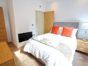 a bedroom with a large white bed with orange pillows at Pass the Keys Mill Conversion Flat Mins from City Bars Shops in Manchester