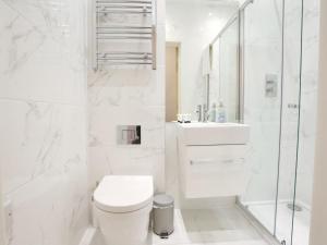 a white bathroom with a toilet and a shower at Pass the Keys Mill Conversion Flat Mins from City Bars Shops in Manchester