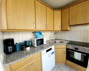 Una cocina con gabinetes de madera y un microondas blanco. en 2 Zimmer für 3-4 Person , Klima, Parkplatz, en Mülheim an der Ruhr