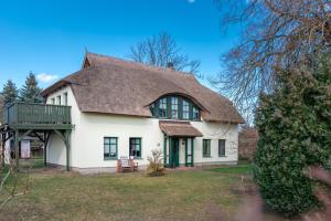 une grande maison blanche avec un toit à la mansarde dans l'établissement Ferienwohnungen "Zur Linde am Achterwasser", à Zempin