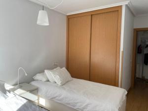 a bedroom with a white bed and a wooden door at La Cabana, Edificio Los Molinos in Felechosa
