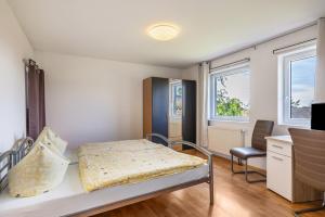 Un pequeño dormitorio con una cama y una silla. en Gästezimmer Gross, en Tübingen