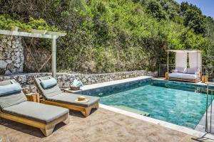 a swimming pool with two chairs and a table and avisor at Villa Kalou Cottage by Villa Plus in Mousata