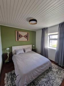 a bedroom with a white bed and a window at Casa Vieira in Fajã da Ovelha