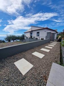 a white house with a building in the background at Casa Vieira in Fajã da Ovelha