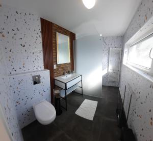 a bathroom with a toilet and a sink and a window at Bed&Beach La Primavera in De Koog