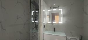 a white bathroom with a sink and a mirror at Premium appart avec piscine et vue sur la ville in Yaoundé