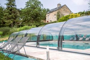 a swimming pool with chairs in a glass house at Domaine de Cantelou in Clécy