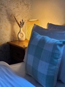 a bed with blue pillows and a vase on a table at Ramsay Lane in Lossiemouth