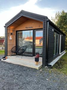 a black tiny house sitting on a wooden deck at Willa Rauha E, minikoti saunalla, iso parkkialue in Lumijoki +10 photos