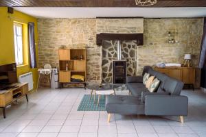 a living room with a couch and a stone wall at Domaine de Cantelou in Clécy