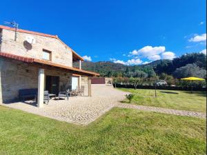 an external view of a stone house with a patio at Casa doNegrinho com Piscina in Monção