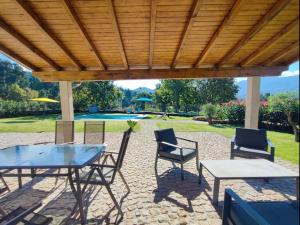 a patio with a table and chairs under a wooden roof at Casa doNegrinho com Piscina in Monção