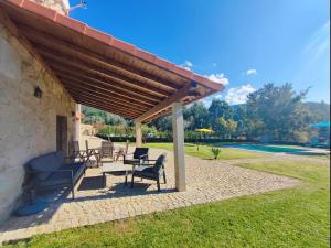 a patio with a table and chairs under a roof at Casa doNegrinho com Piscina in Monção