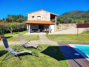 a couple of chairs sitting on the grass near a house at Casa doNegrinho com Piscina in Monção +47 photos