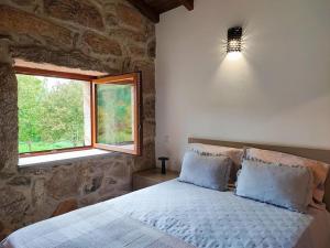 a bedroom with a large bed and a window at Casa doNegrinho com Piscina e Bungalow sem Piscina in Monção