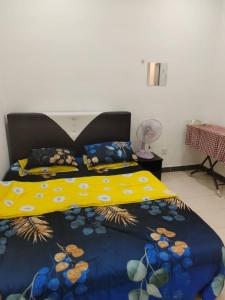 a bedroom with a bed with a blue and yellow comforter at Mateen Cottage II in Tanah Rata