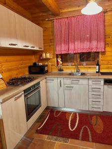 a kitchen with white cabinets and a red window at Kuća za odmor Petra in Jasenak