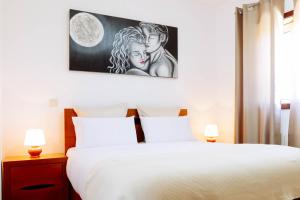 Un dormitorio con una cama blanca y un cuadro en la pared. en Casa Fundevila Celorico de Basto by AloTur, en Celorico de Basto