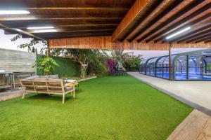 an outdoor patio with a green lawn and a glass building at אחוזת כנען - וילה מדהימה עם בריכה פרטית מחוממת וג'קוזי in Yarka