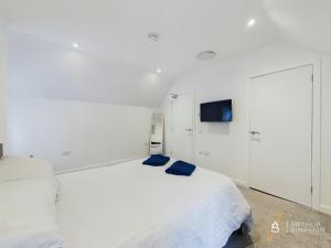 Habitación blanca con 2 camas y TV de pantalla plana. en Modern Commercial Street Maisonette, en Lerwick