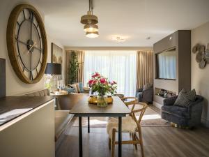 sala de estar con mesa y reloj grande en la pared en Converted Church, Lamlash Shorefront, Arran Shores Garden Terrace Apartment 6, en Lamlash