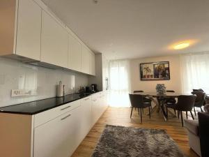 Modern Apt with top location in Kloten في كلوتان: مطبخ مع دواليب بيضاء وطاولة مع كراسي