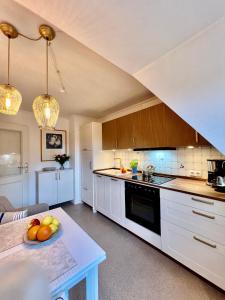 a kitchen with white cabinets and a table with a bowl of fruit at Annika1 in Tinnum