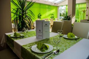 a dining table with a green tablecloth and glasses on it at Viktória Wellness Hotel in Nagyatád